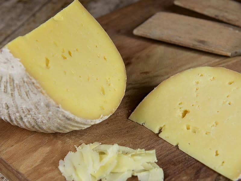 Fine Cheesemakers of Scotland: The Ethical Dairy's Rainton Tomme wedge on a wooden cheeseboard.